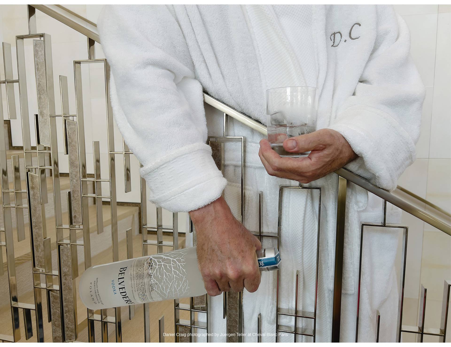 Daniel Craig in robe holding glass and bottle